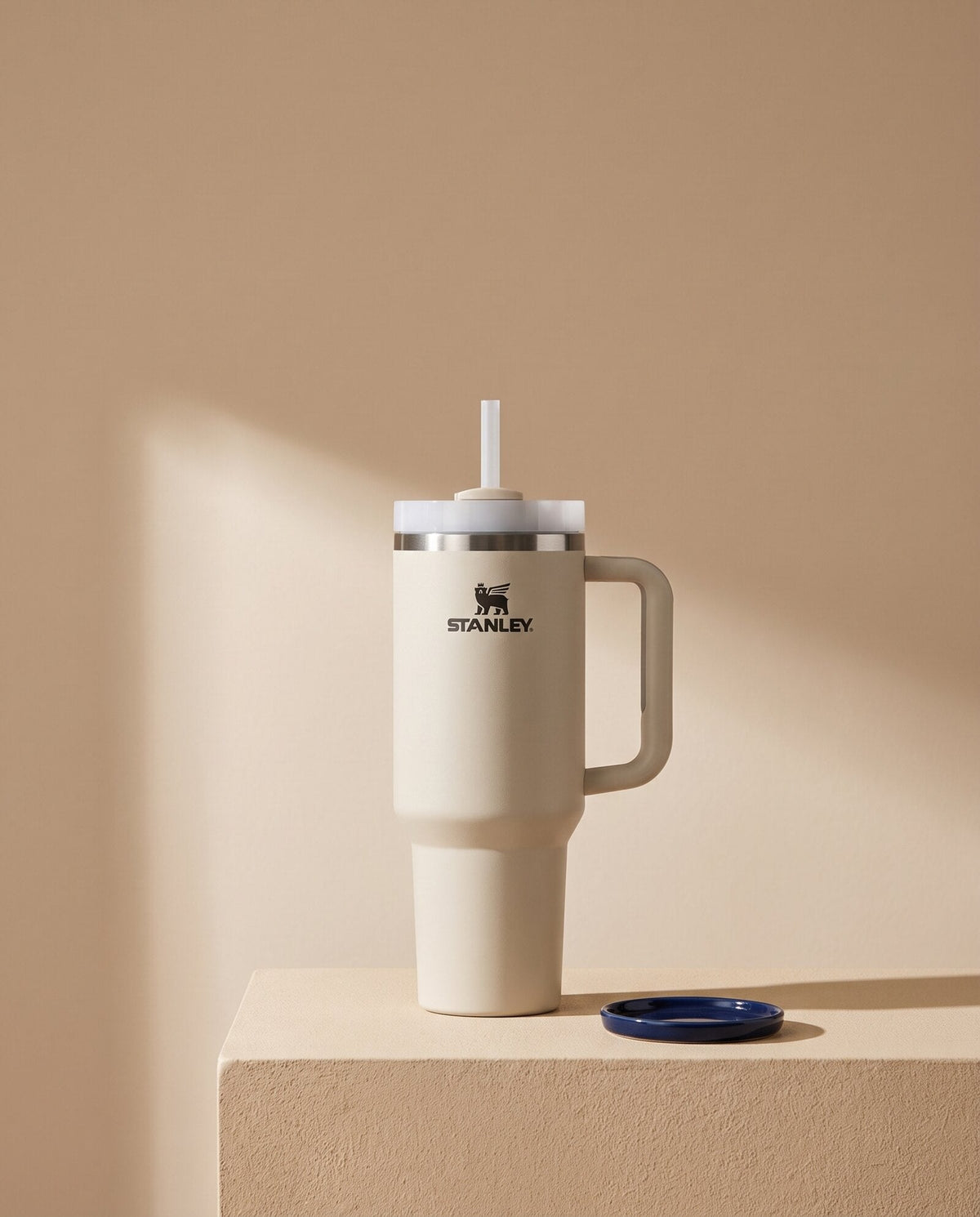 Vaso Stanley Quencher color blanco sobre pedestal beige